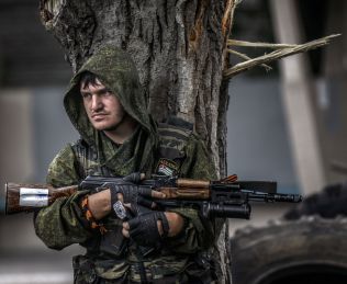 ANSPENT: En prorussisk separatist søker dekning bak et tre i utkanten av byen Donetsk. Byen har vært åsted for harde kamper mellom separatister og ukrainske regjeringsstyrker.